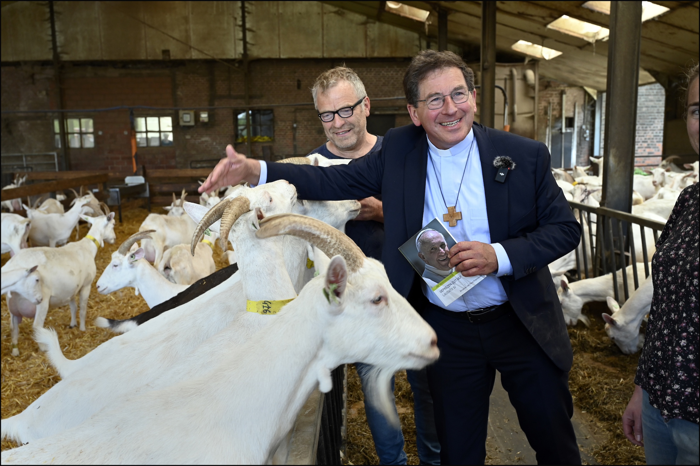 Bisschop Lode Aerts lacht naar de camera terwijl hij voelt aan de warme hoorns van een geitje.