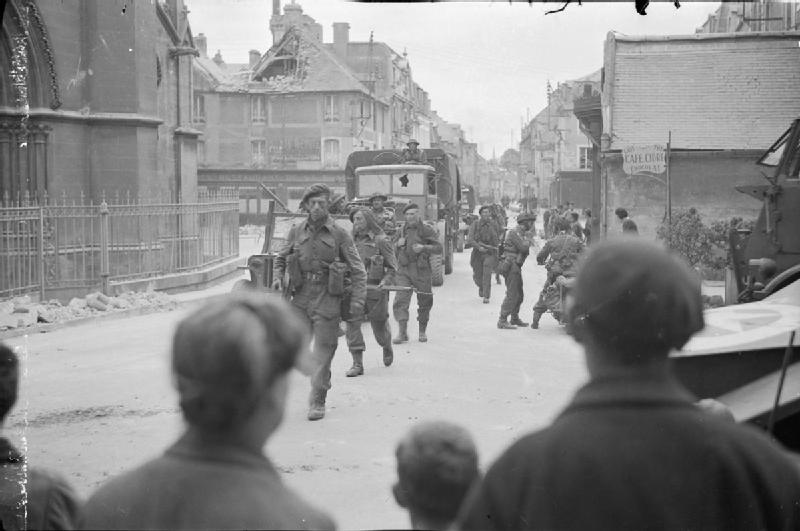 Britse troepen trekken door het dorp Douvres la Delivrande in juni 1944 onder het oog van Franse burgers