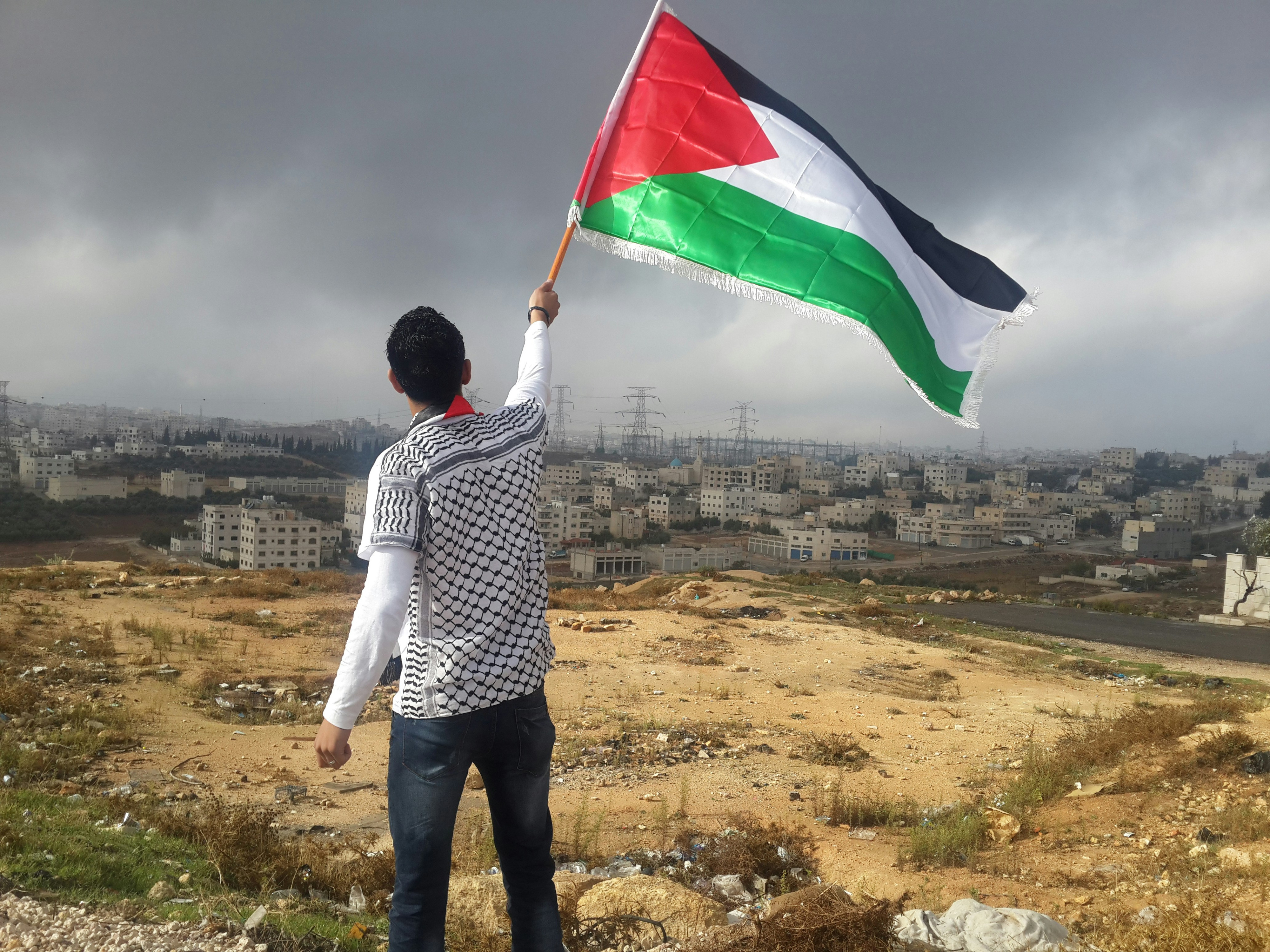 Kind zwaait met Palestijnse vlag terwijl het uitkijkt over een verwoest Gaza.