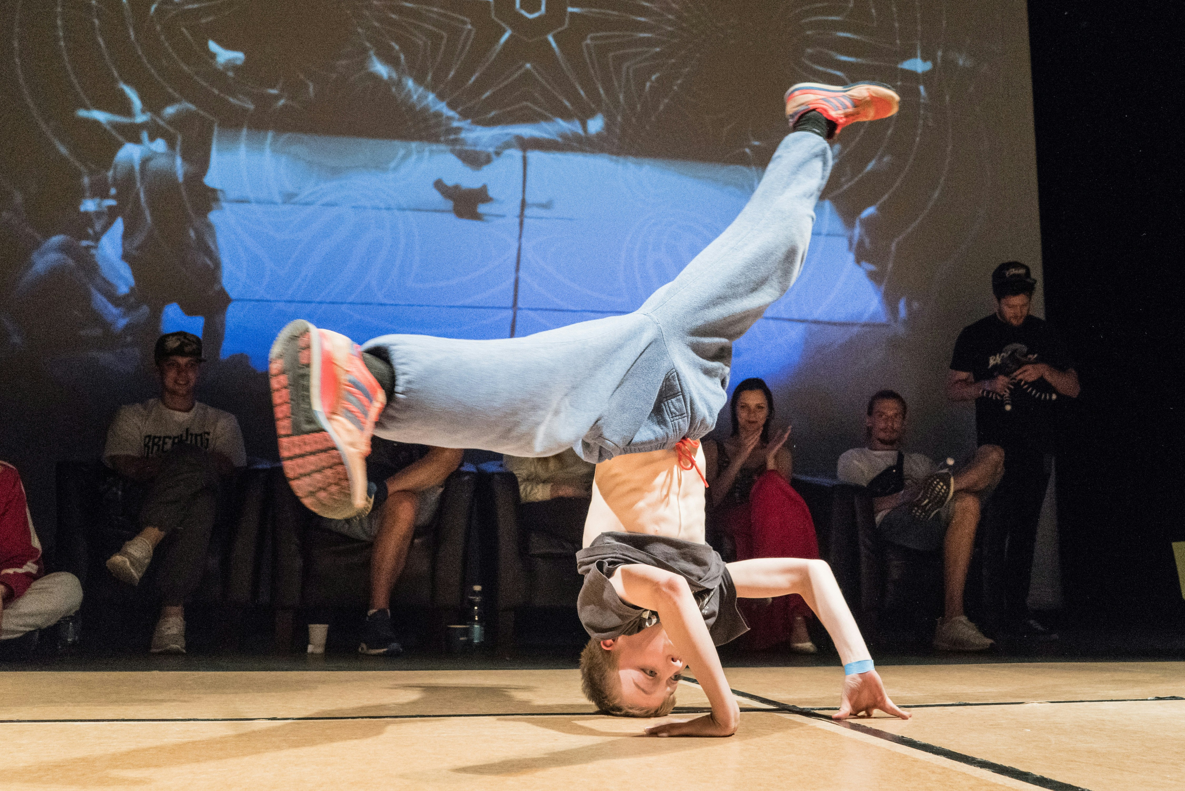 Meisje - B-girl - draait rondje op hoofd met benen in spreidstand.