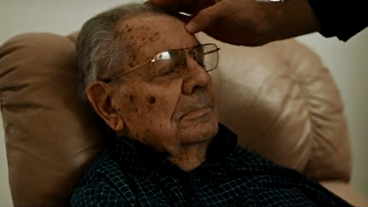 Ziekenzalving: hand tekent kruisje op voorhoofd van een oude man. 