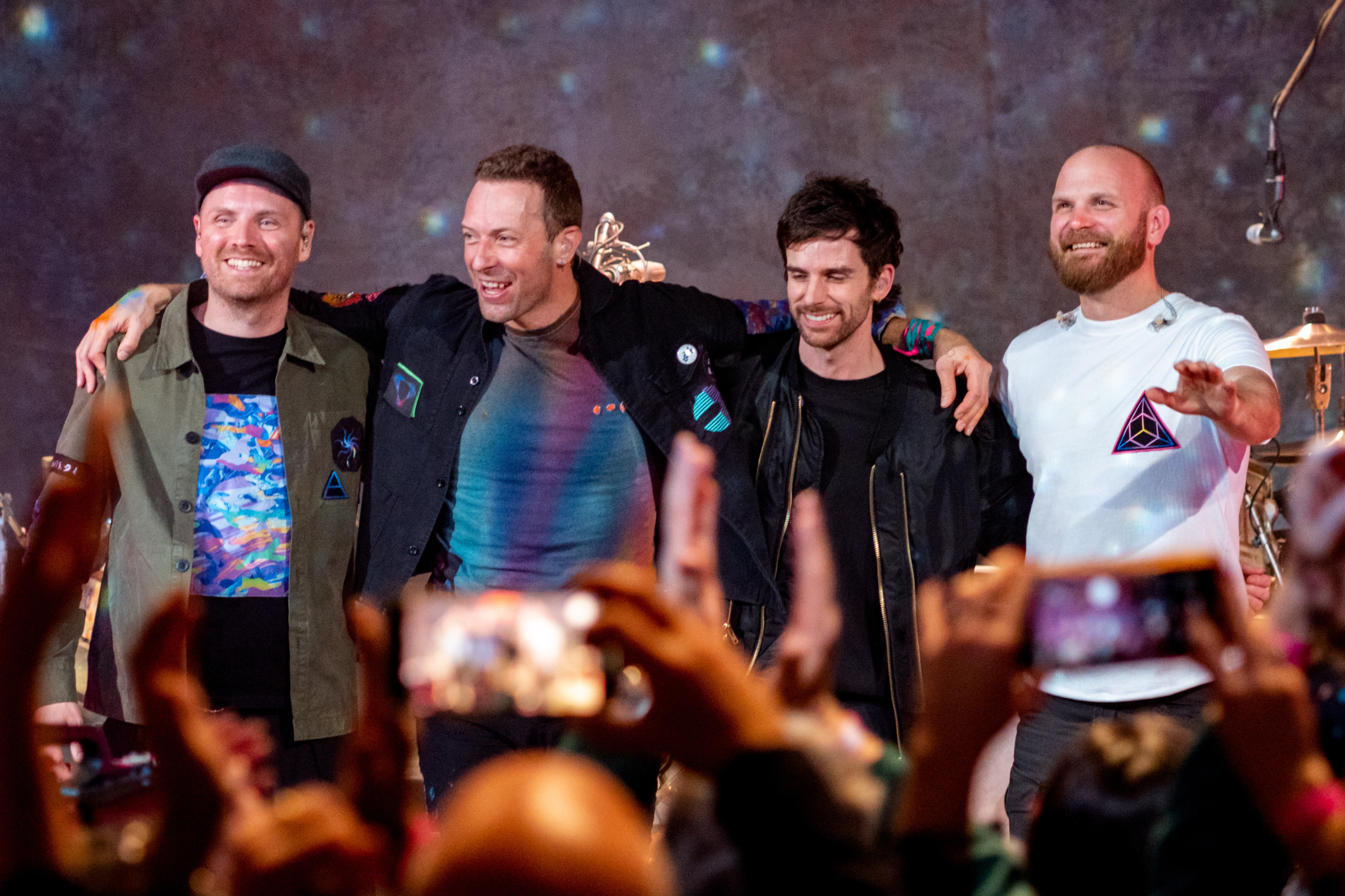 De vierkoppige Britse band Coldplay met frontman Chris Martin, armen over elkaar en klaar voor een buiging na een concert.