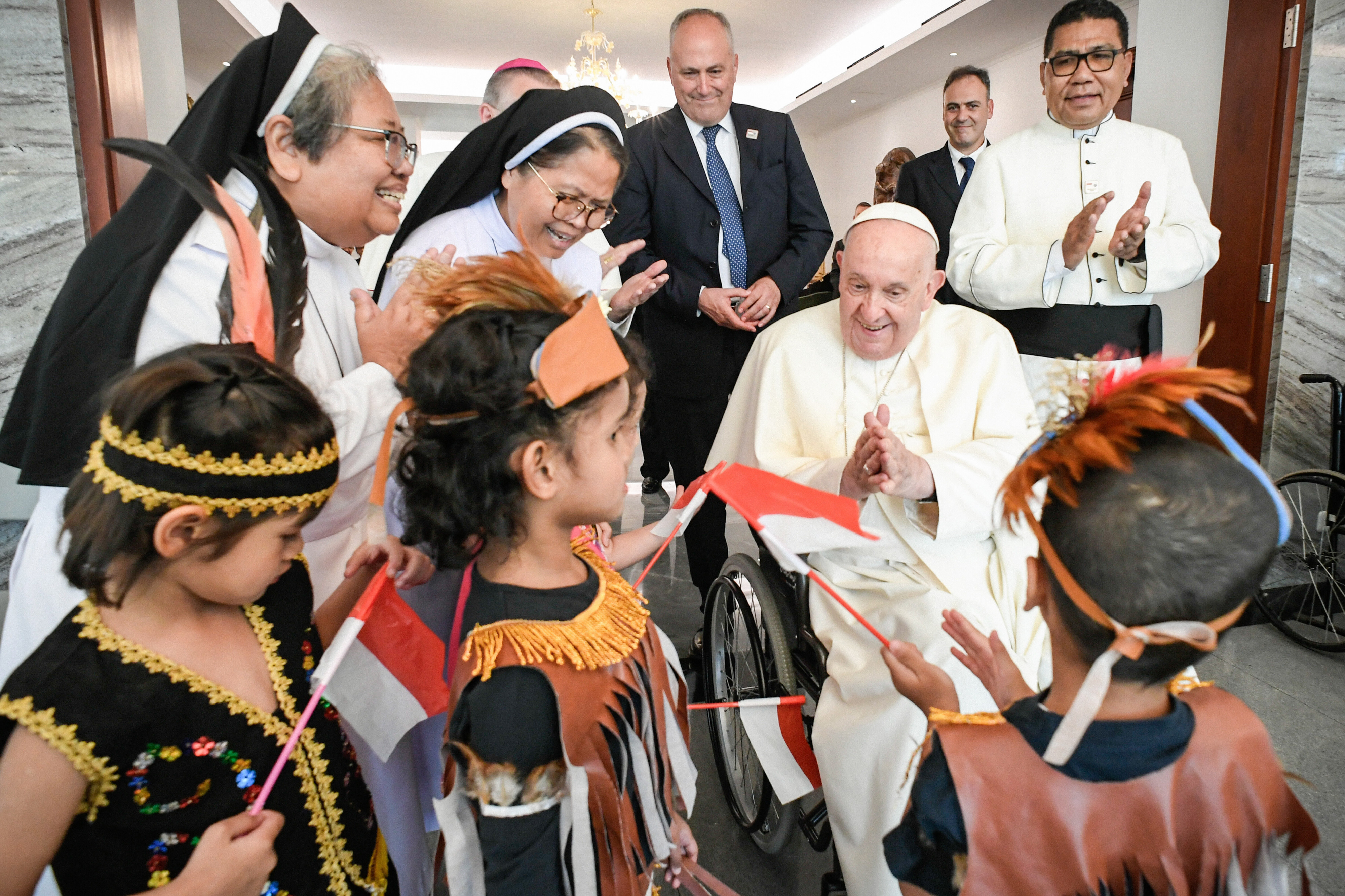 De paus wordt in Indonesië begroet door kinderen in traditionele kledij.