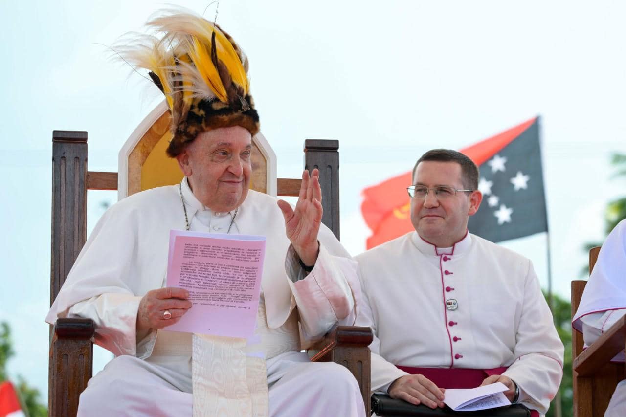 Paus Franciscus met traditionele hoofdtooi uit Papoua-Nieuw-Guinea, een kroon met gele veren.