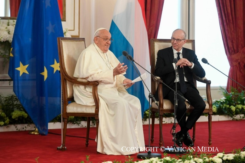 De paus zit naast de premier in het Cultureel Centrum van Luxemburg en spreekt de aanwezigen toe.