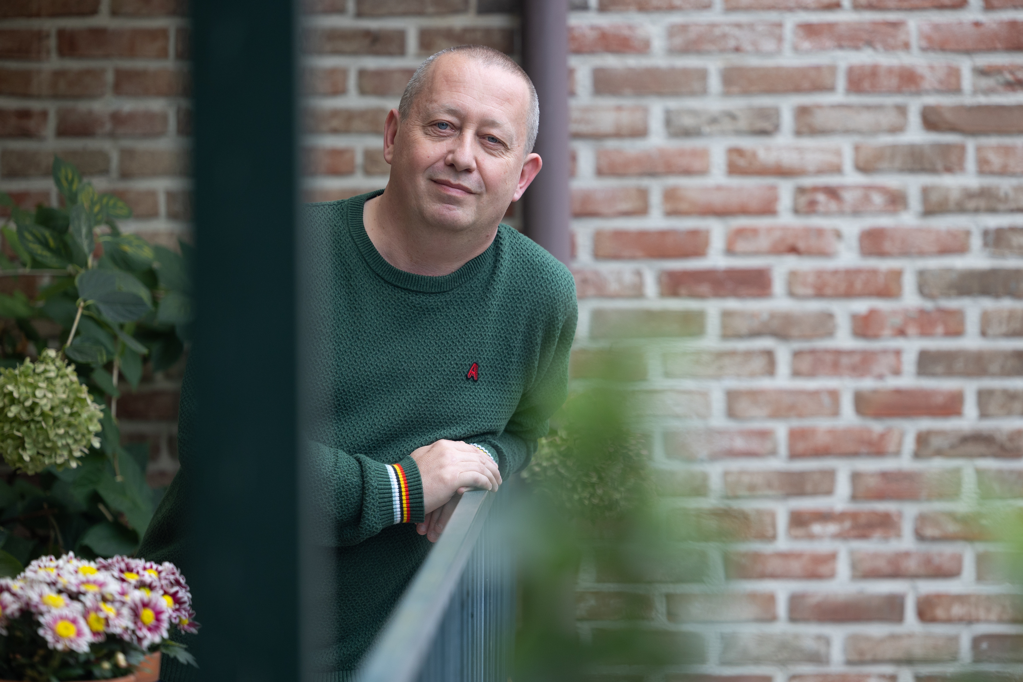 Mark Janssens leunt over zijn balkon en kijkt de camera in de ogen.