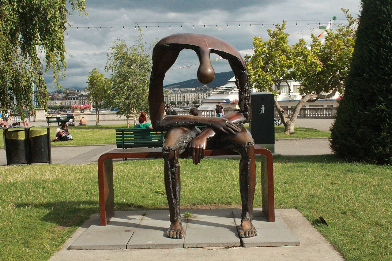 Het beeld bestaat uit een grote bronzen figuur die op een bank zit. Op de plaats waar zich normaal de romp bevindt, is een groot gat te zien.