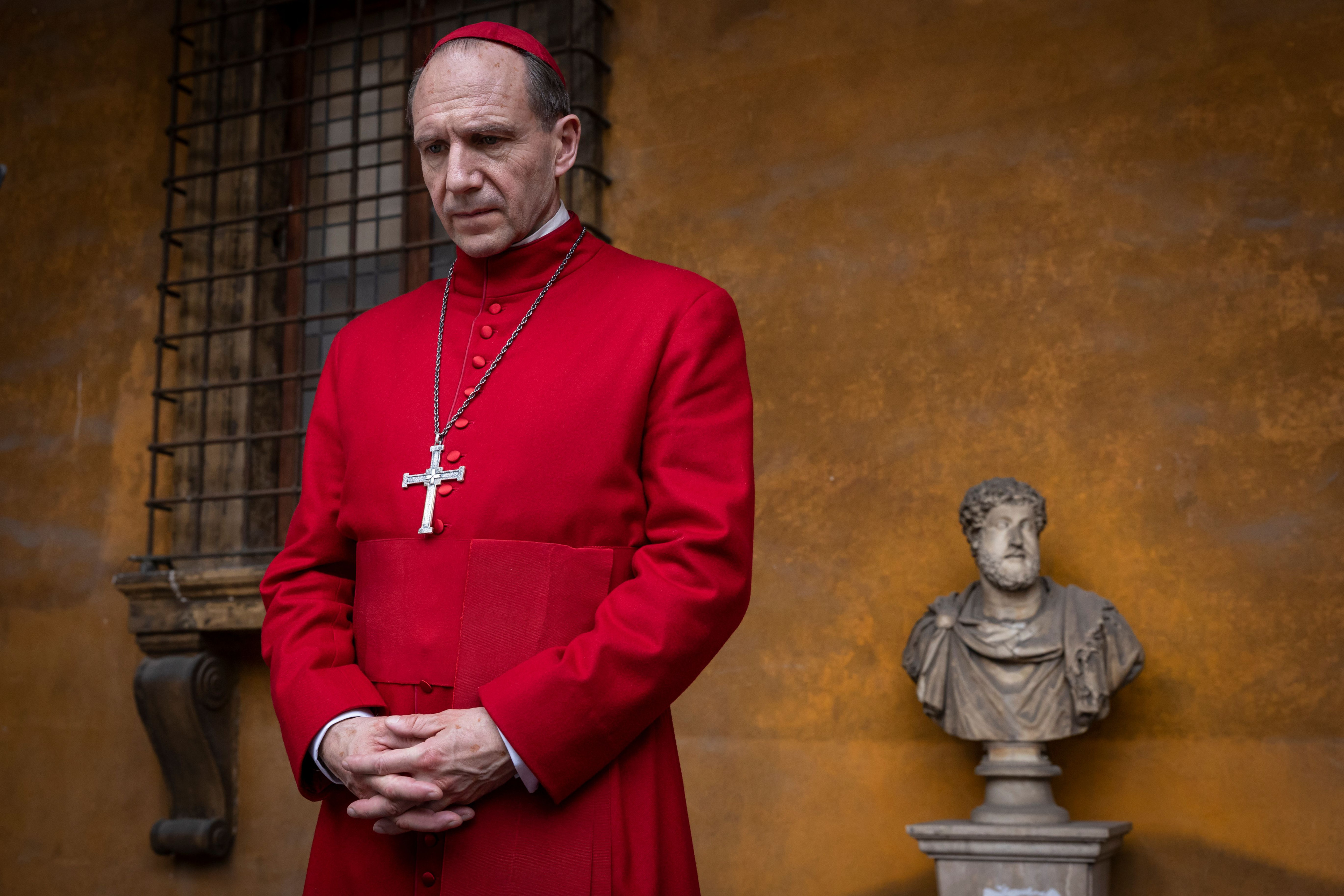 Kardinaal Lawrence (Ralph Fiennes) kijkt in de film Conclave vanaf het balkon van het Vaticaan neer op de kardinalen die toekomen voor het conclaaf