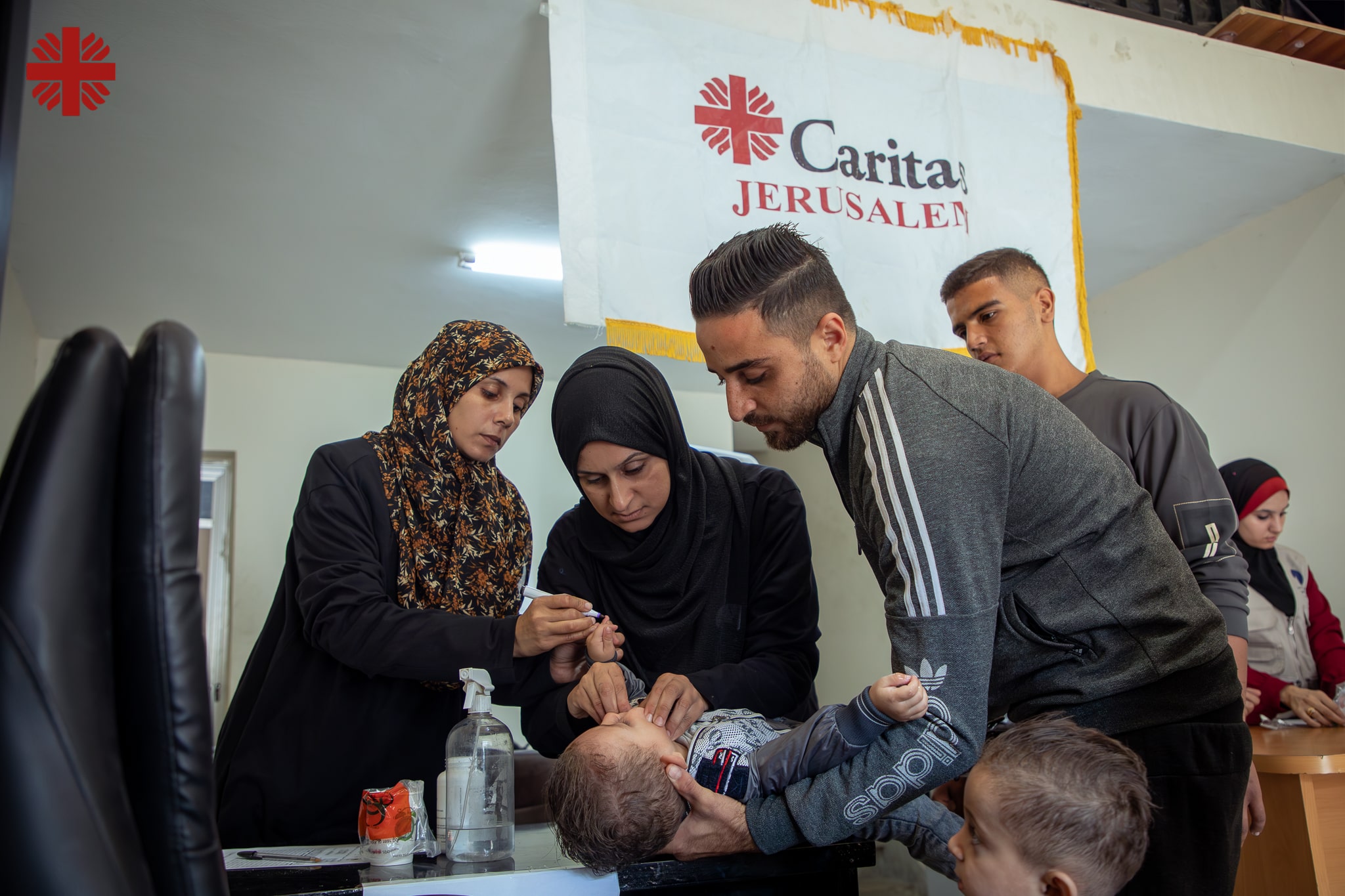 Een ziek kind wordt bij de hulpverleners van Caritas gebracht.