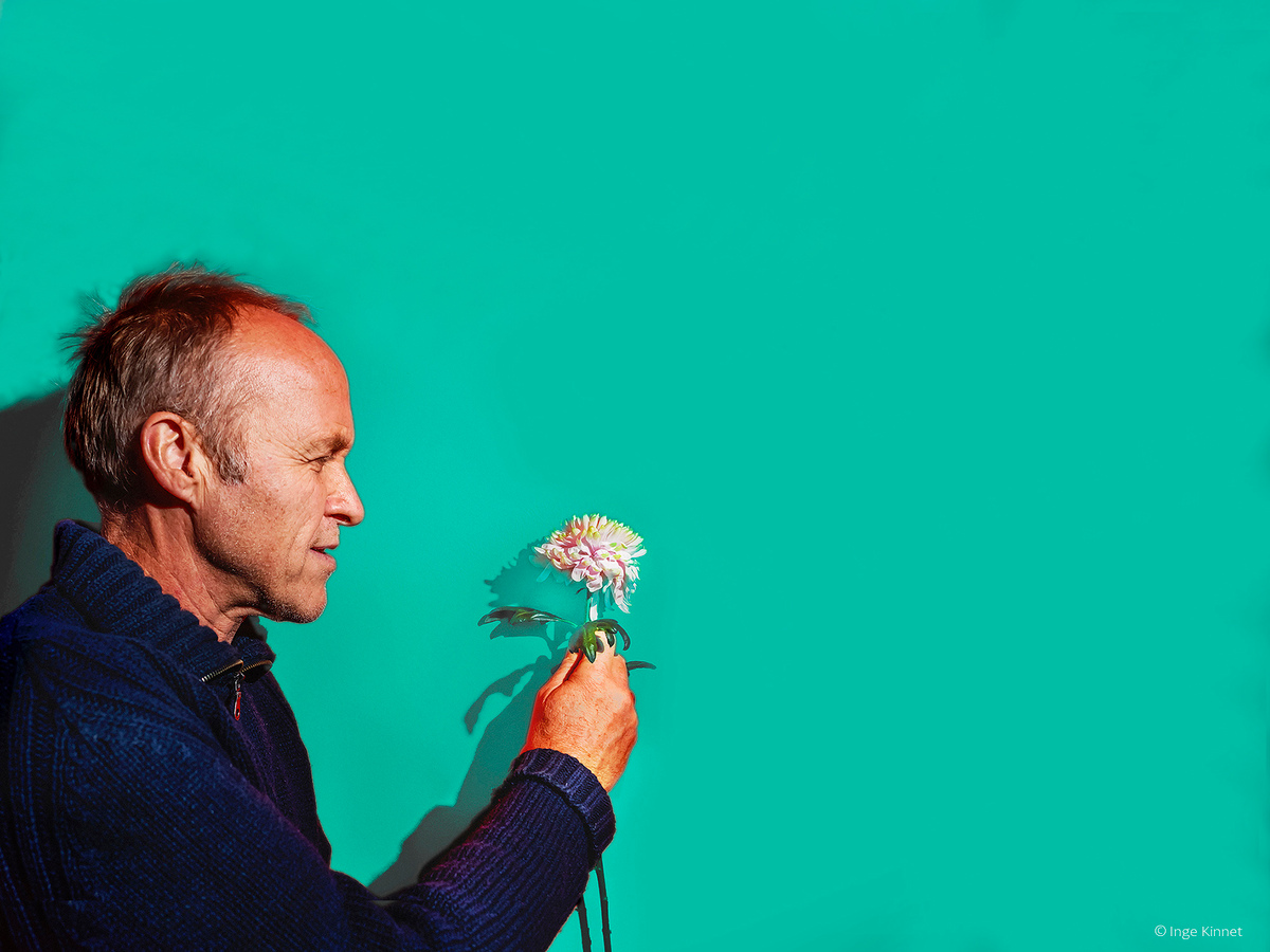 Stef Bos met bloemetje in de hand tegen effen groene achtergrond