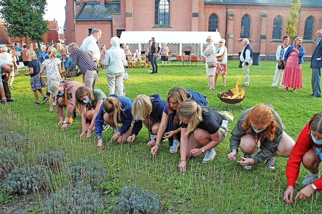 Jongeren planten bloemen, met op de achtergrond de brandende vuurschaal. © Rachel Van Hoof