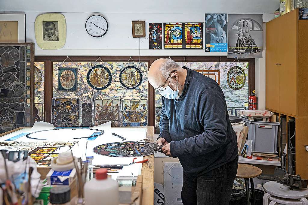 Joost Caen in zijn atelier in de weer met de restauratie van het glasraam uit de dertiende eeuw. © Ans Brys