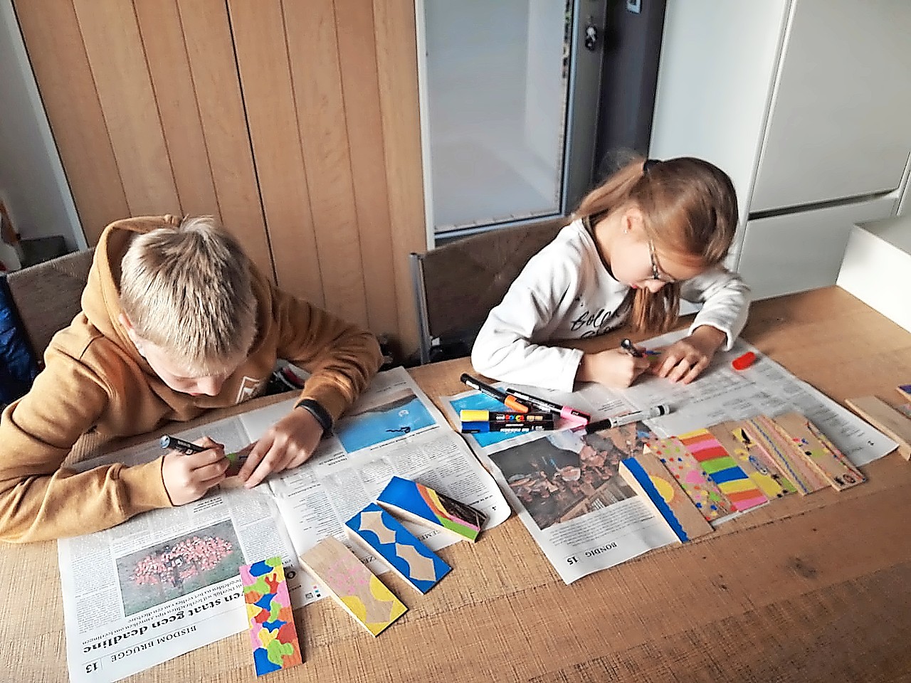 Kinderen helpen de houten peggen versieren en geven ze aldus een persoonlijke touch. © Riet Tack