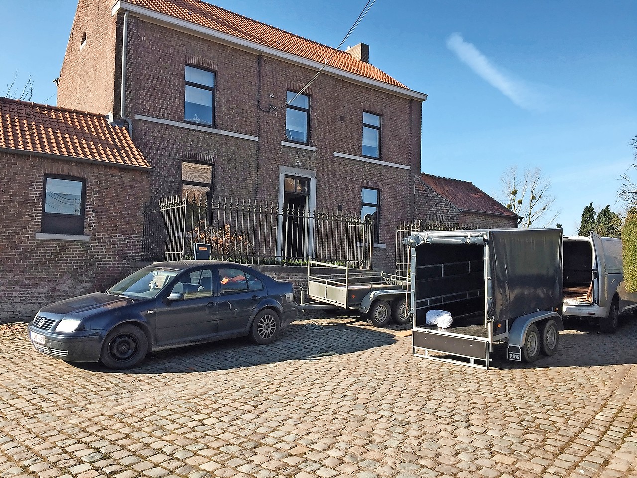 Auto’s met aanhangwagens rijden﻿ heen en weer om het huis in te richten. © Serge Casier