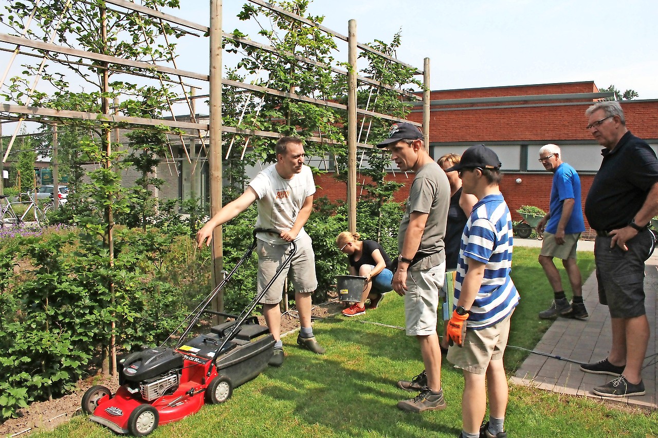 Vrijwilligers en bewoners werken samen om de tuin van de zorgvoorziening weer in orde te maken. © Nathalie Geerkens