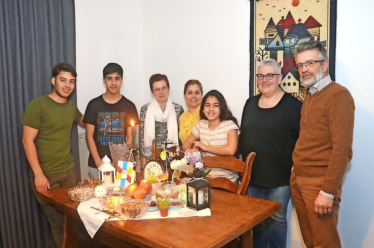 De familie Biglari en hun begeleiders aan de traditionele feesttafel. © Tony Dupont