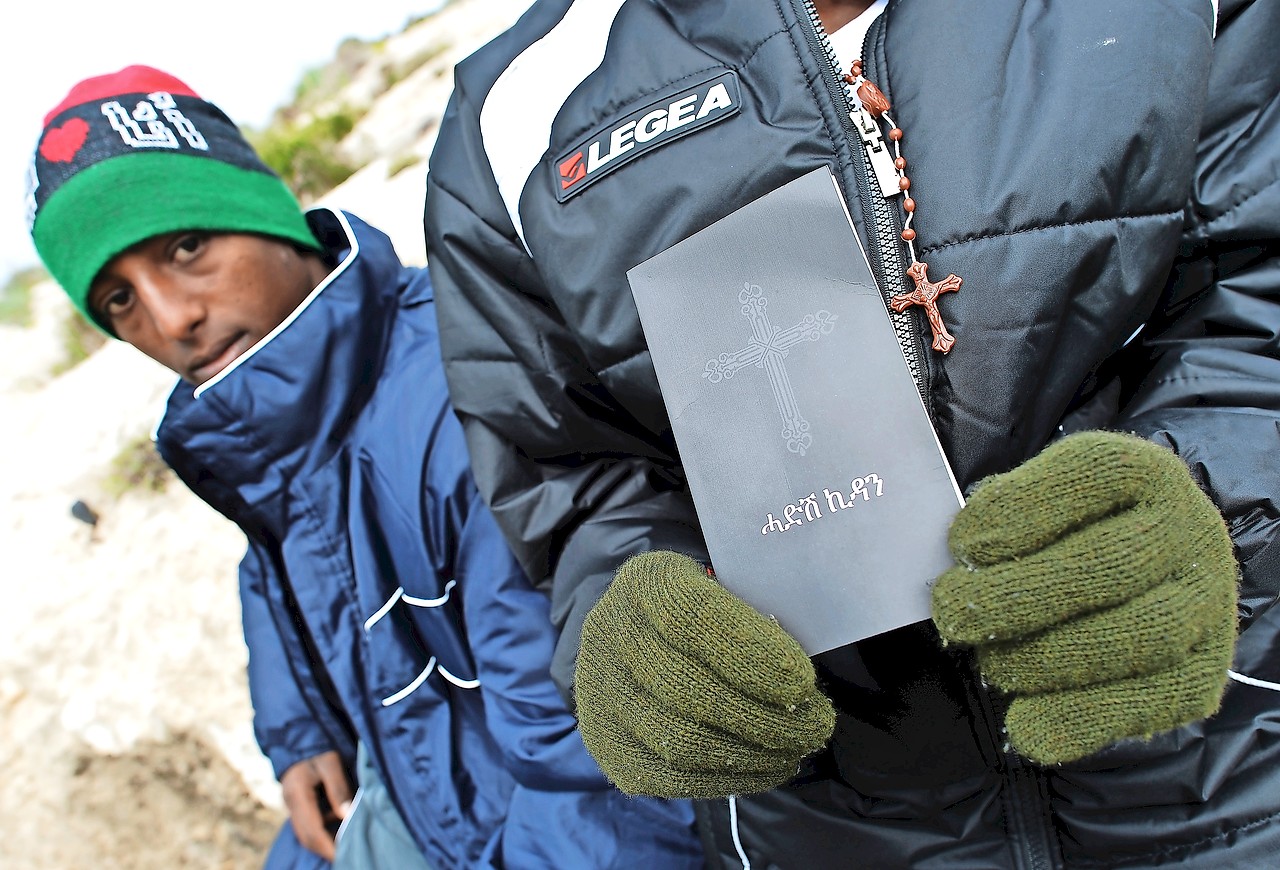 Eritrese vluchtelingen op het Italiaanse Lampedusa tonen een Bijbel in hun taal. © Belga Image