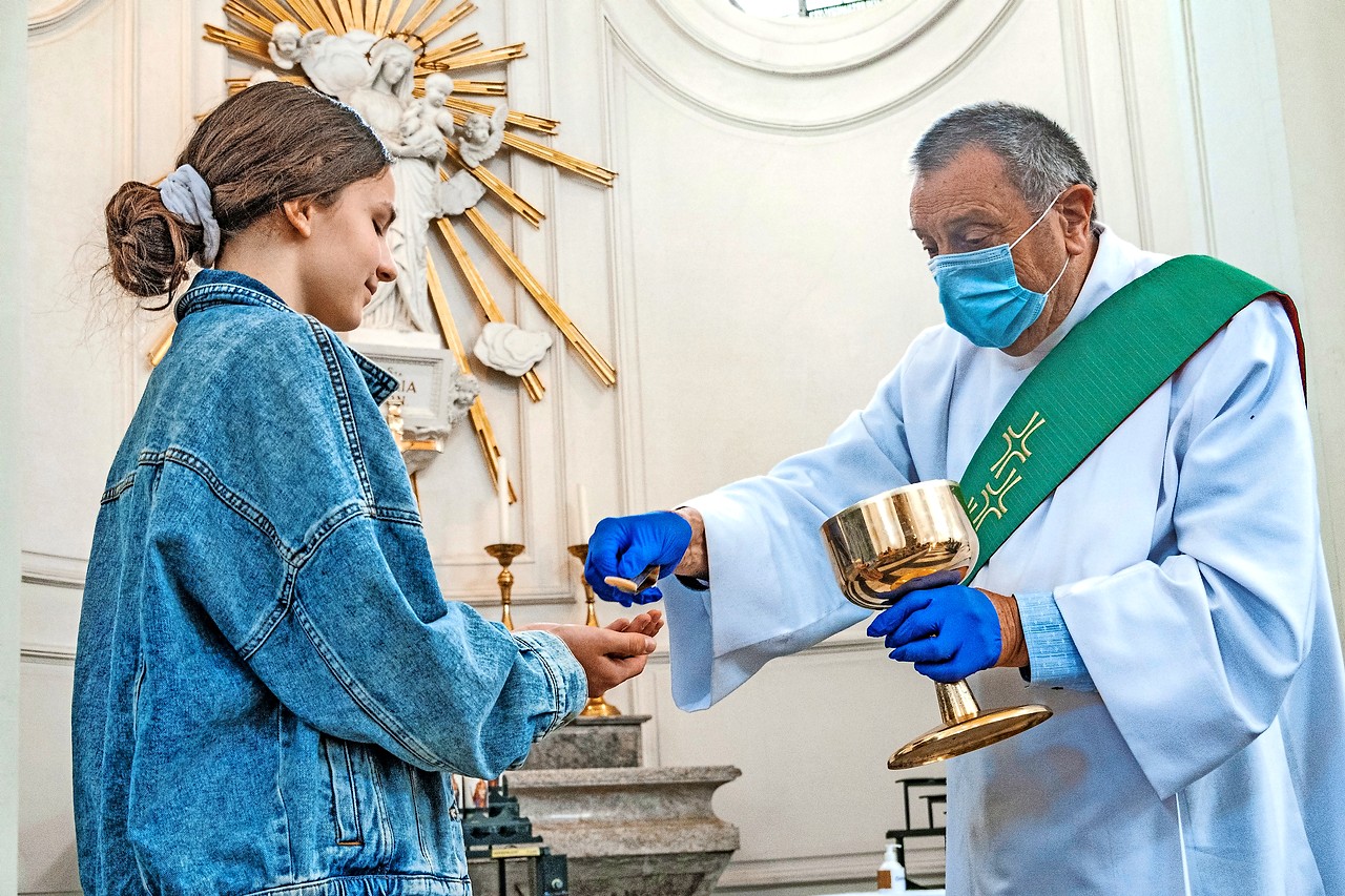 Uitreiking van de communie met mondmasker en handschoenen behoren tot het ‘nieuwe normaal’. © Luk Vanmaercke