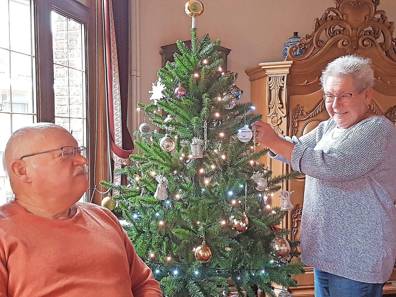 Luc Camps en Josephina Bosmans vinden troost bij de kerstboom en het kerstdorp op hun dressoir. © Ilse Van Halst