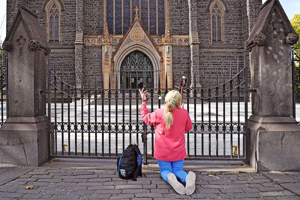 Een vrouw bidt tijdens de lockdown aan Saint Patrick’s Cathedral in Melbourne. © Belga Image