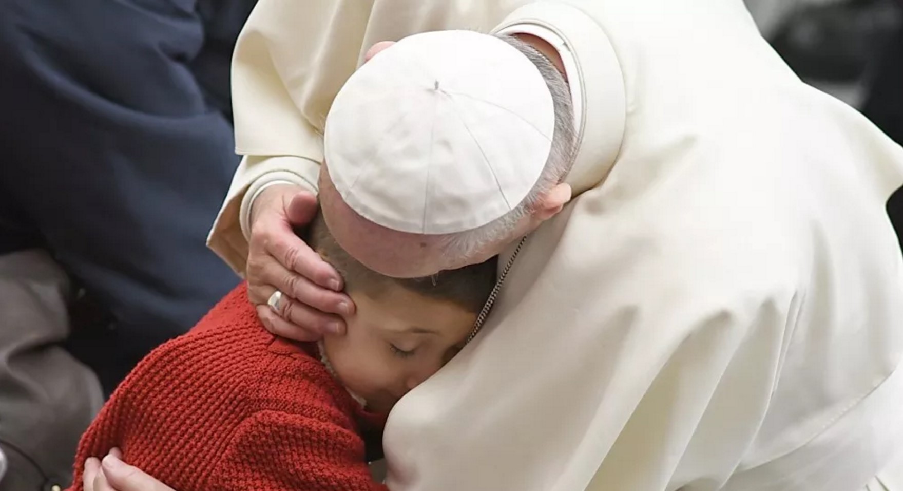 Paus Franciscus knuffelt een kind tijdens de algemene audiëntie