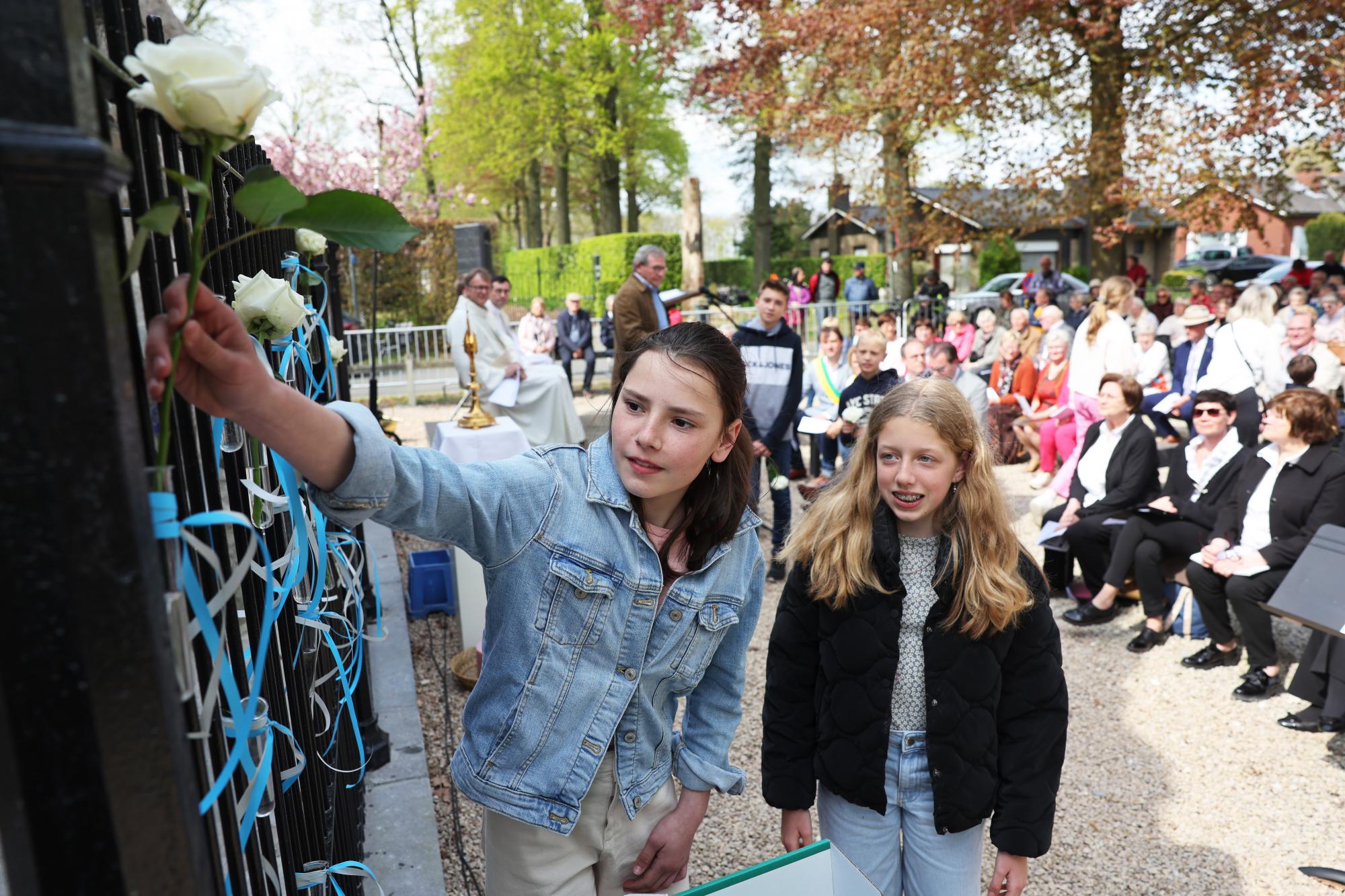 Opvallend veel jeugdige deelnemers tekenden present bij de herinzegening. Ze hingen blauwe linten op aan het hek rond de grot.