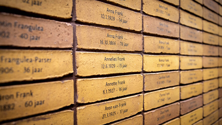 Het Holocaust Namenmonument in Amsterdam. Je herkent de naam van Anne Frank. Boven de installatie zweven de letters van het Hebreeuwse woord voor 'gedenk'.