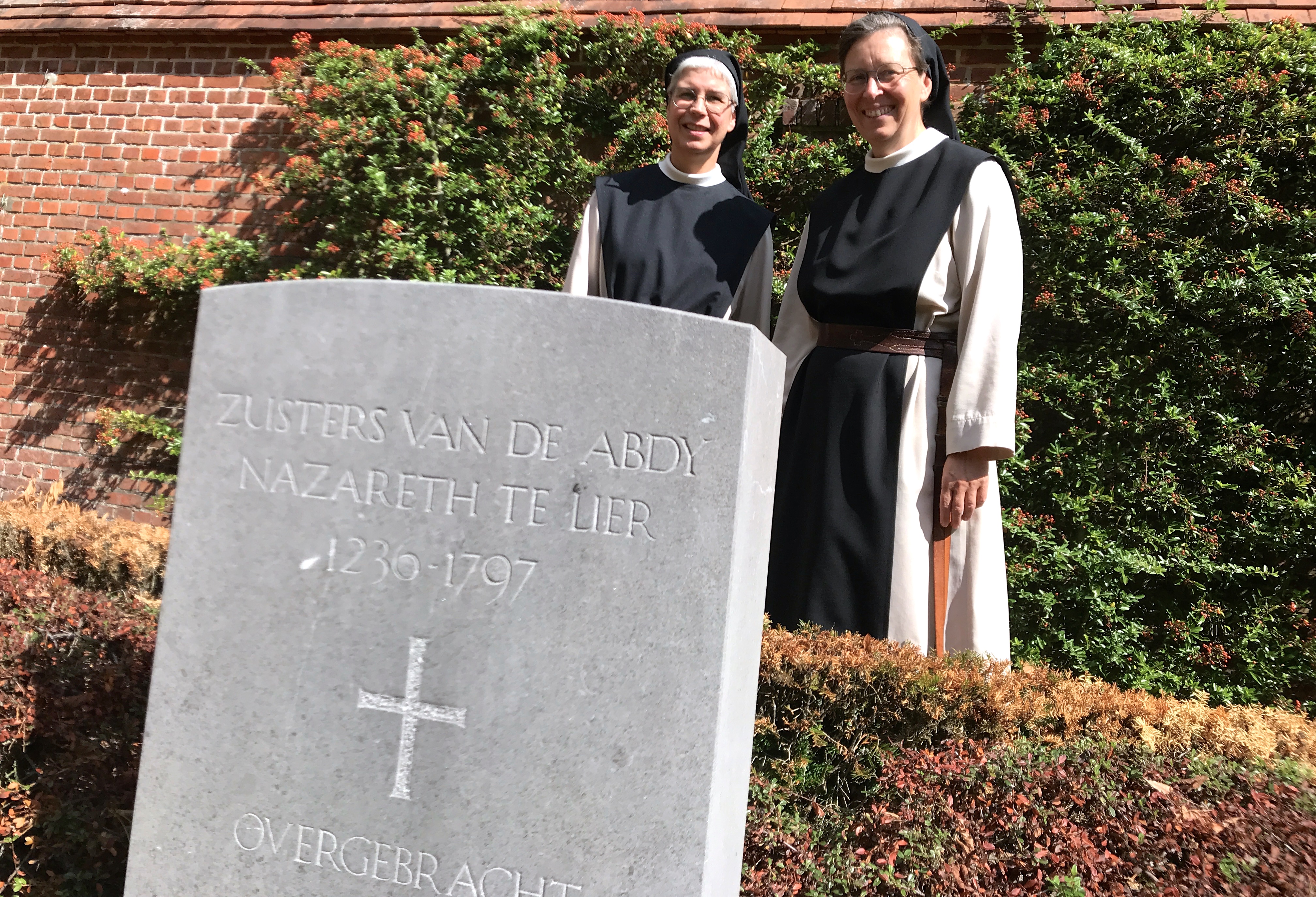 Zuster Anna (links) en zuster Katharina bij de grafsteen waar de resten begraven liggen van zusters van de abdij in Lier.