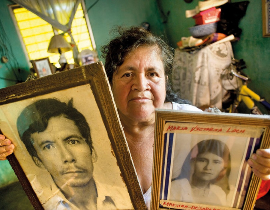 Een nabestaande uit Santa Lucia Cotzumalguapa toont portretten van familieleden die omkwamen bij de boerenprotesten in de jaren 1980.