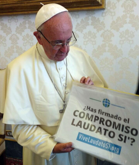 Paus Franciscus met de affiche van de campagne: 'Heb je de Laudato Si-belofte al getekend?'