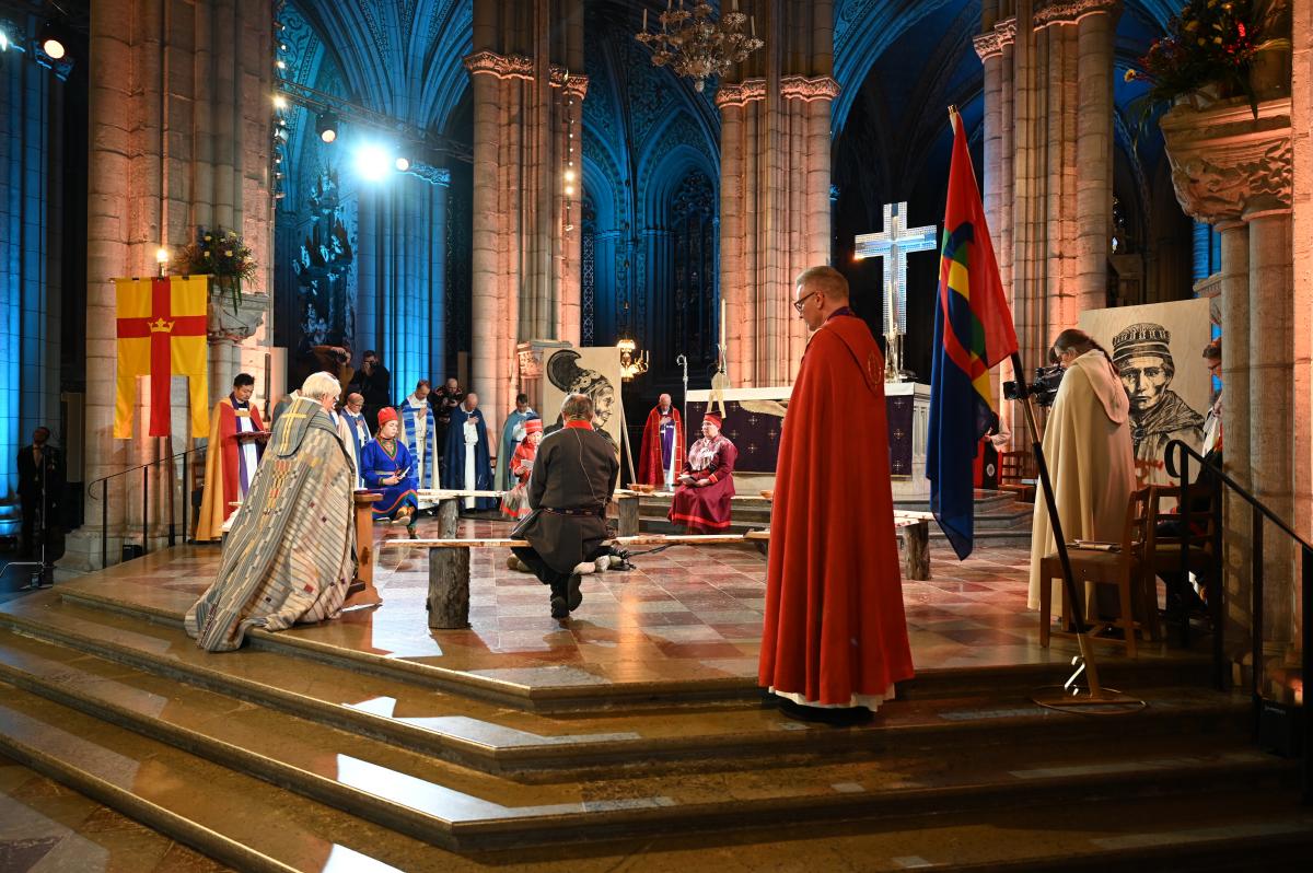 Aartsbisschop Antje Jackelén knielt voor een groep Sámi-vertegenwoordigers in de kathedraal van Uppsala